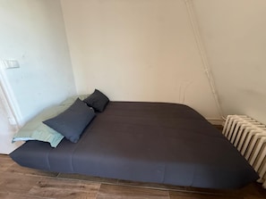 Et værelse med en seng, en radiator og en stikkontakt.