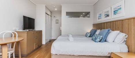 Un dormitorio moderno con una cama, mesita de noche y televisor sobre un aparador.