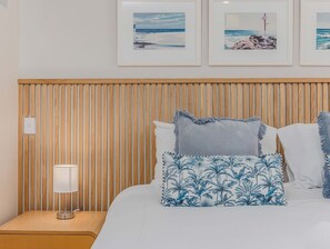 A neatly made bed with a wooden headboard, a bedside lamp, and a tropical patterned pillow. - The Sand Resort | Coastal Studio with park view (Kingscliff)