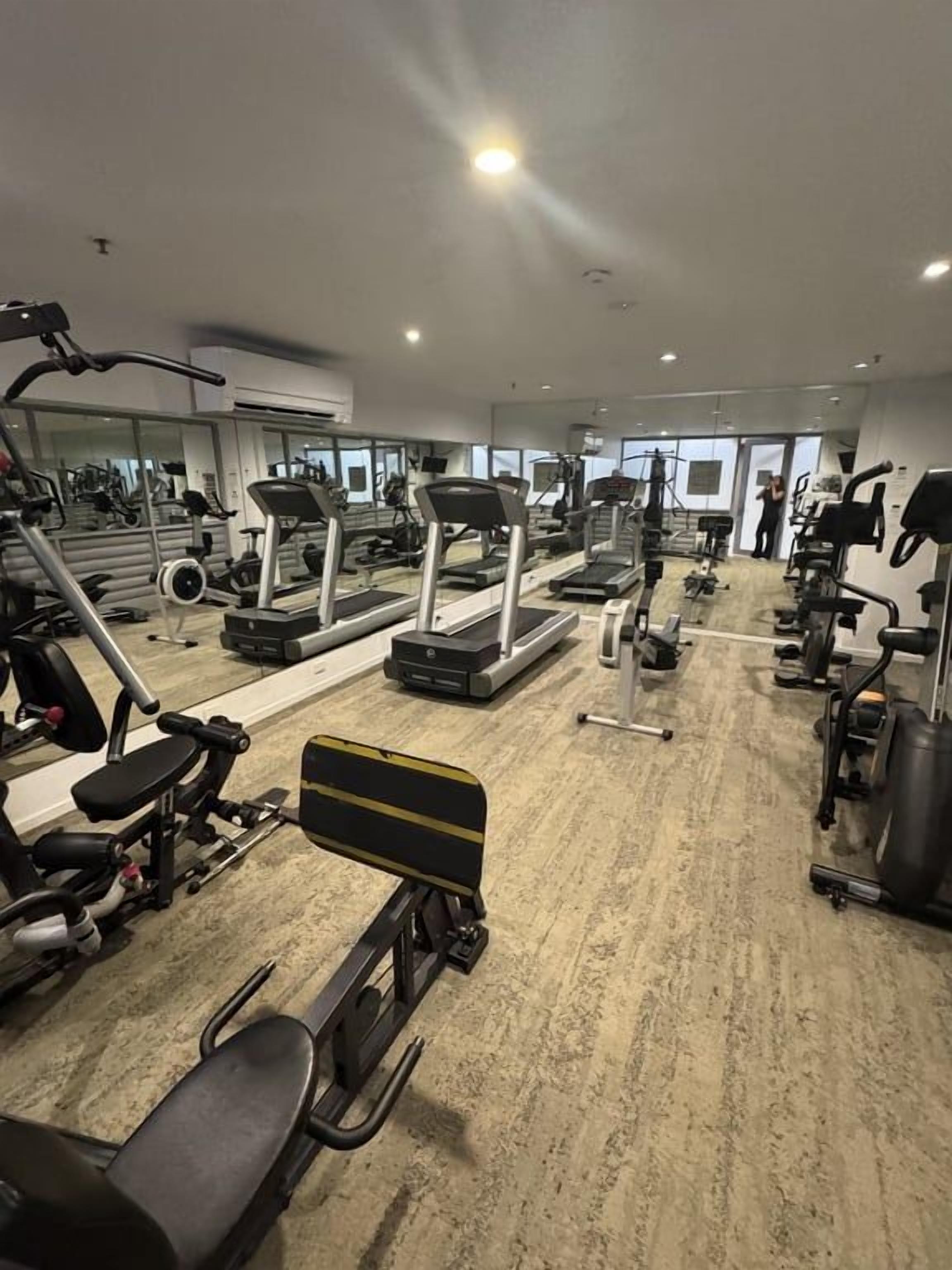 Une salle de sport équipée de tapis de course, d’appareils de musculation et d’autres équipements d’exercice.