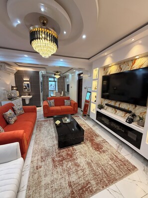 A modern living room with a sofa, coffee table, and a flat-screen TV. - Modern Haven Ultimate Coastal Getaway, Modern & Serene (Mombasa)