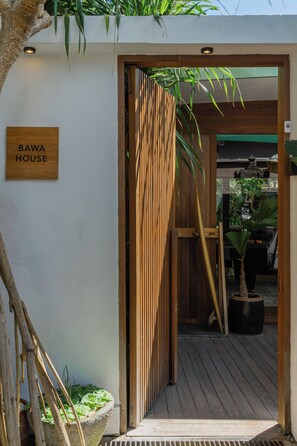 A wooden door with a sign reading 'BAWA HOUSE' and a wooden fence with vertical slats. - Bawa House (Pererenan)