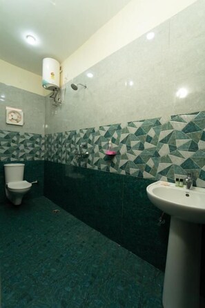 Casa de banho com sanita, lavatório e parede com padrão de azulejos geométricos.
