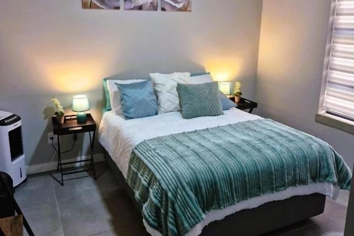 A bedroom with a bed, nightstands, a heater, and wall art.