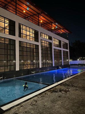 A building with a swimming pool and a covered area with lights.