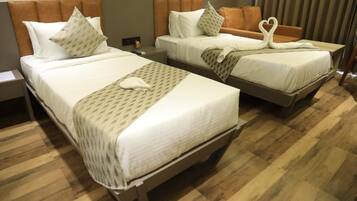A hotel room with two beds, each with a headboard, pillows, and a blanket.
