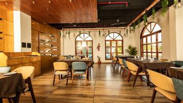 A restaurant with wooden flooring, multiple dining tables, and chairs.