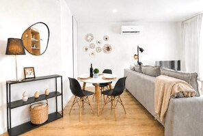 Ein moderner Wohnraum mit Essbereich, einer Couch und einem Fernseher.
