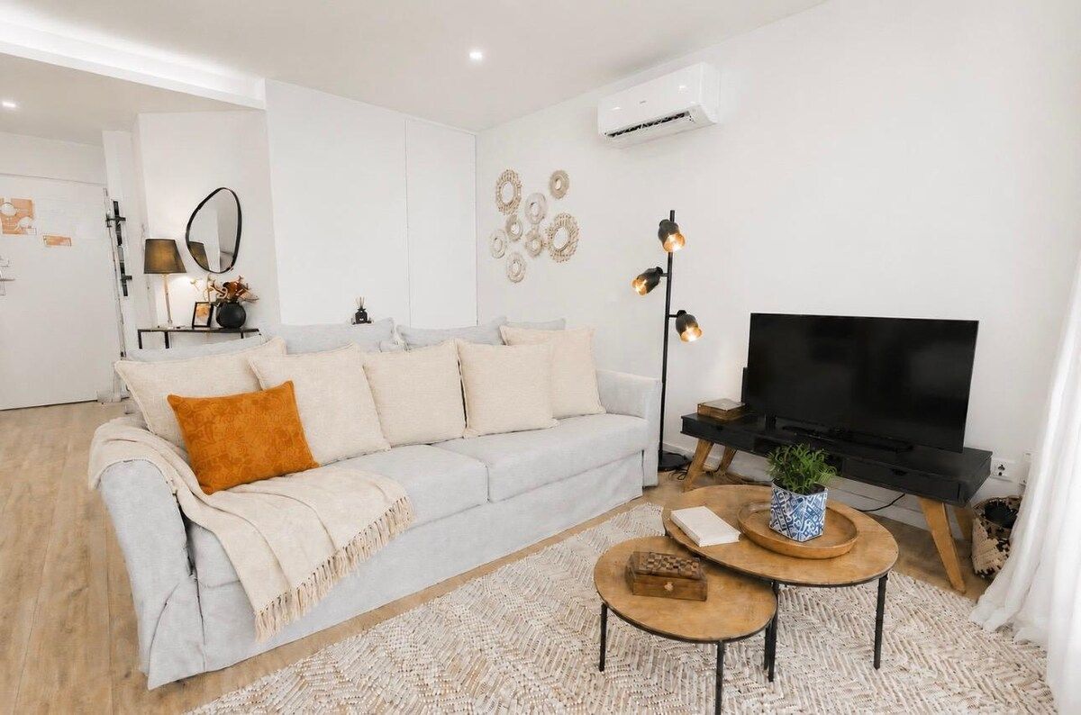 A modern living room with a sofa, a coffee table, a TV, and decorative wall art.