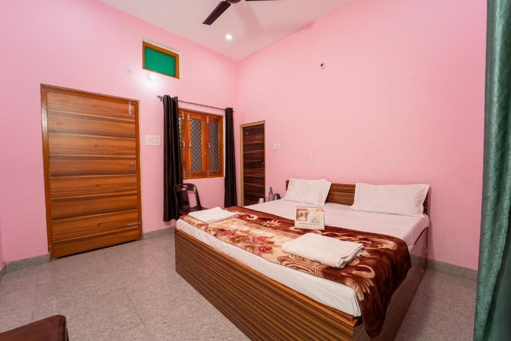 A bedroom with a bed, a wooden wardrobe, a ceiling fan, and a green light fixture.