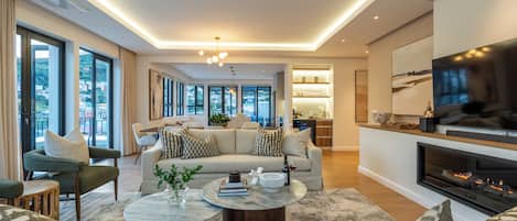 A modern living room with a sofa, two coffee tables, a fireplace, and a television.