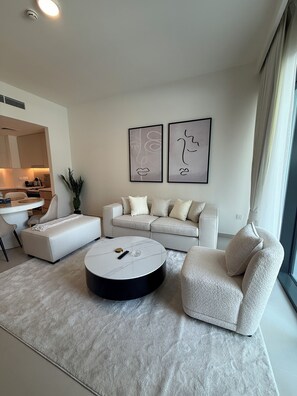 Un salon moderne avec un canapé, une table basse ronde et un fauteuil. Deux œuvres d’art encadrées ornent le mur.