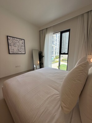 Une chambre d’hôtel avec un grand lit, une vue sur un immeuble par la fenêtre et une œuvre d’art murale.