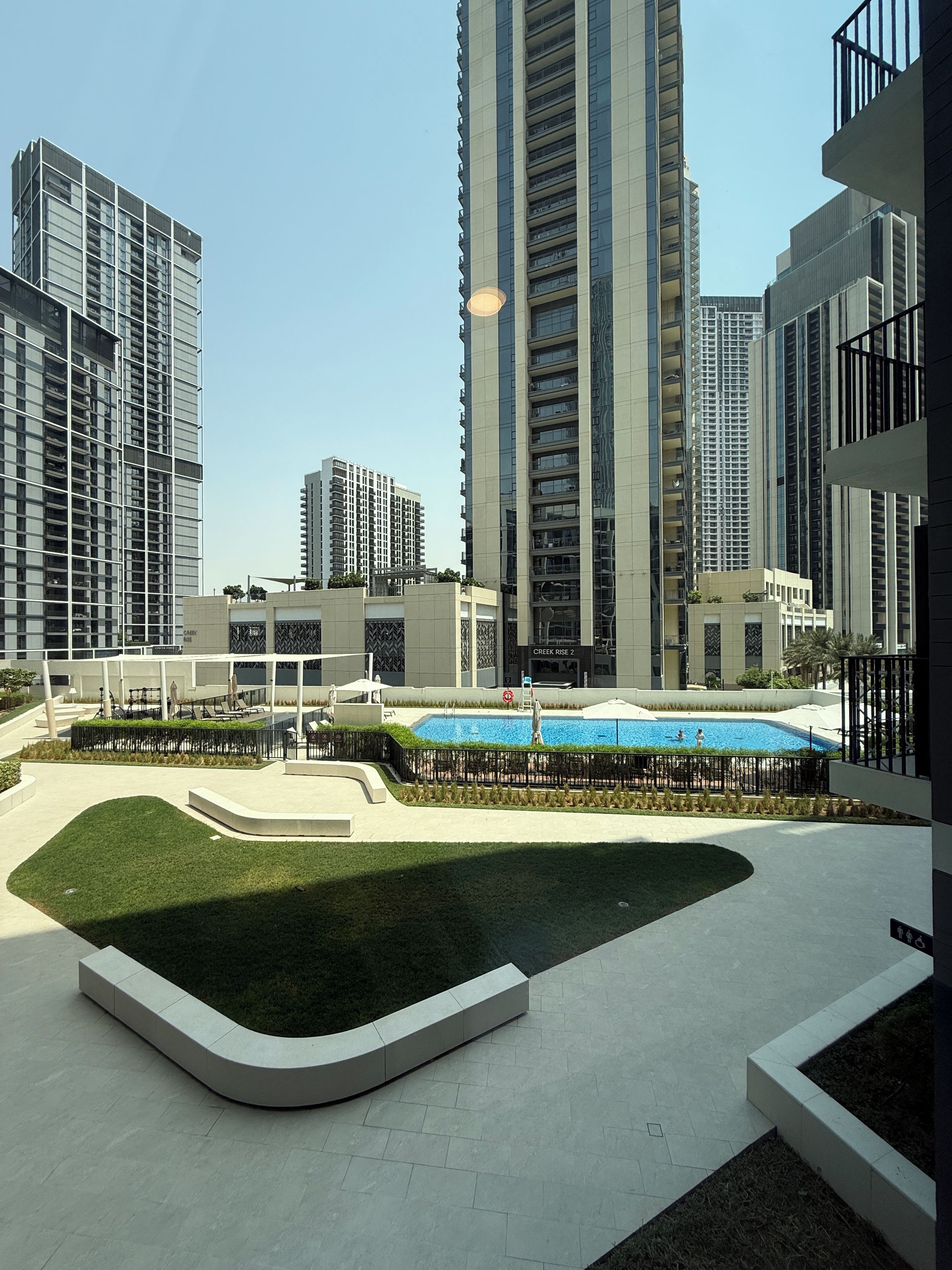 A modern residential complex with high-rise buildings, a swimming pool, and a landscaped courtyard.