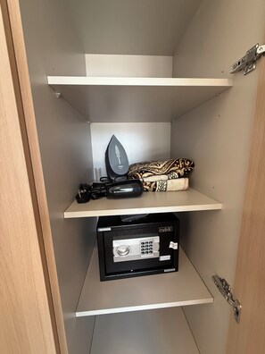 A storage unit with a flat iron, a black device, and a patterned item on the top shelf. - 1-BHK - Dubai Creek Harbor - Pool View (Dubai)