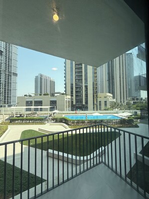 A residential building with a pool, balconies, and modern architecture. - 1-BHK - Dubai Creek Harbor - Pool View (Dubai)
