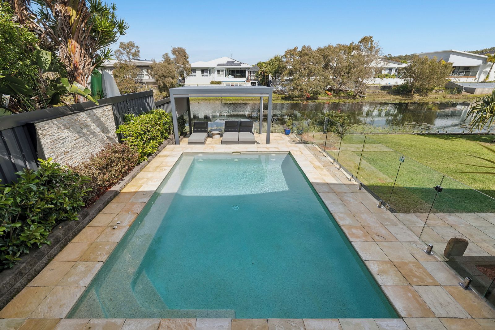A rectangular swimming pool with a clear blue water surface, surrounded by a tiled deck.
