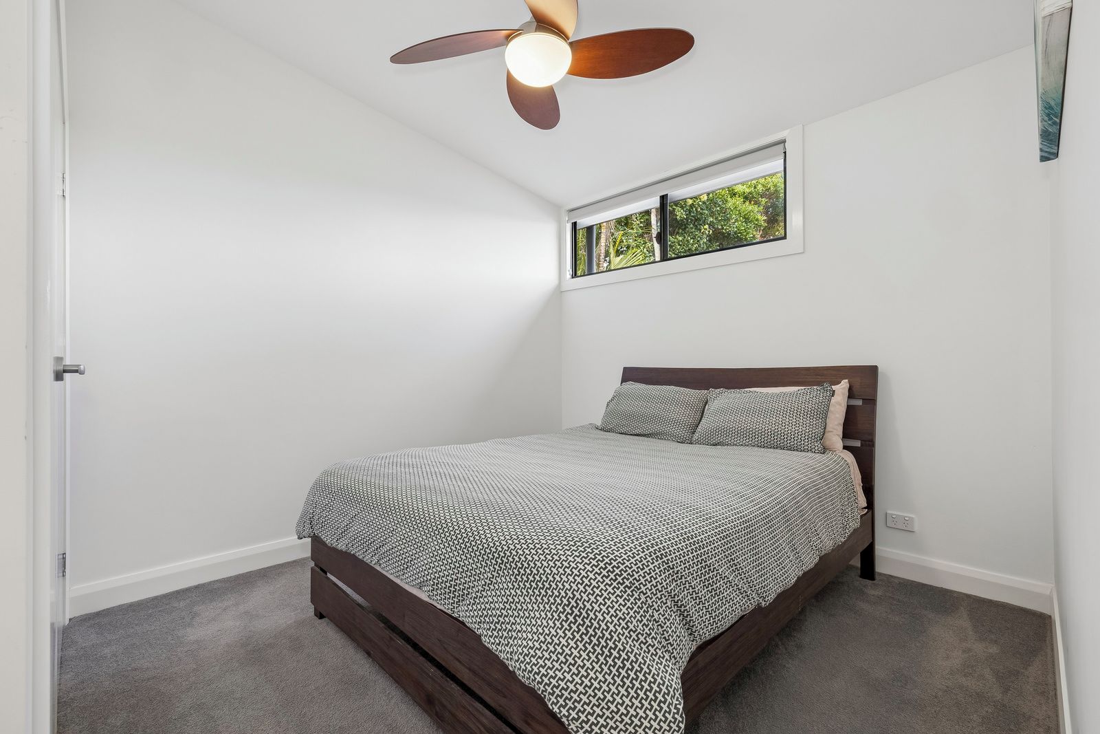A bedroom with a bed, a ceiling fan, a window, and a door.