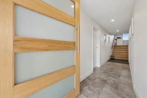 Ein Flur mit einer Holztür, einer Treppe und einem Fliesenboden.