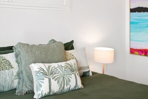Ein Bett mit vielen Kissen, einer Lampe und einem Bild an der Wand.