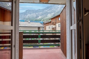 A view through a doorway to a mountain landscape with buildings and a wooden fence.