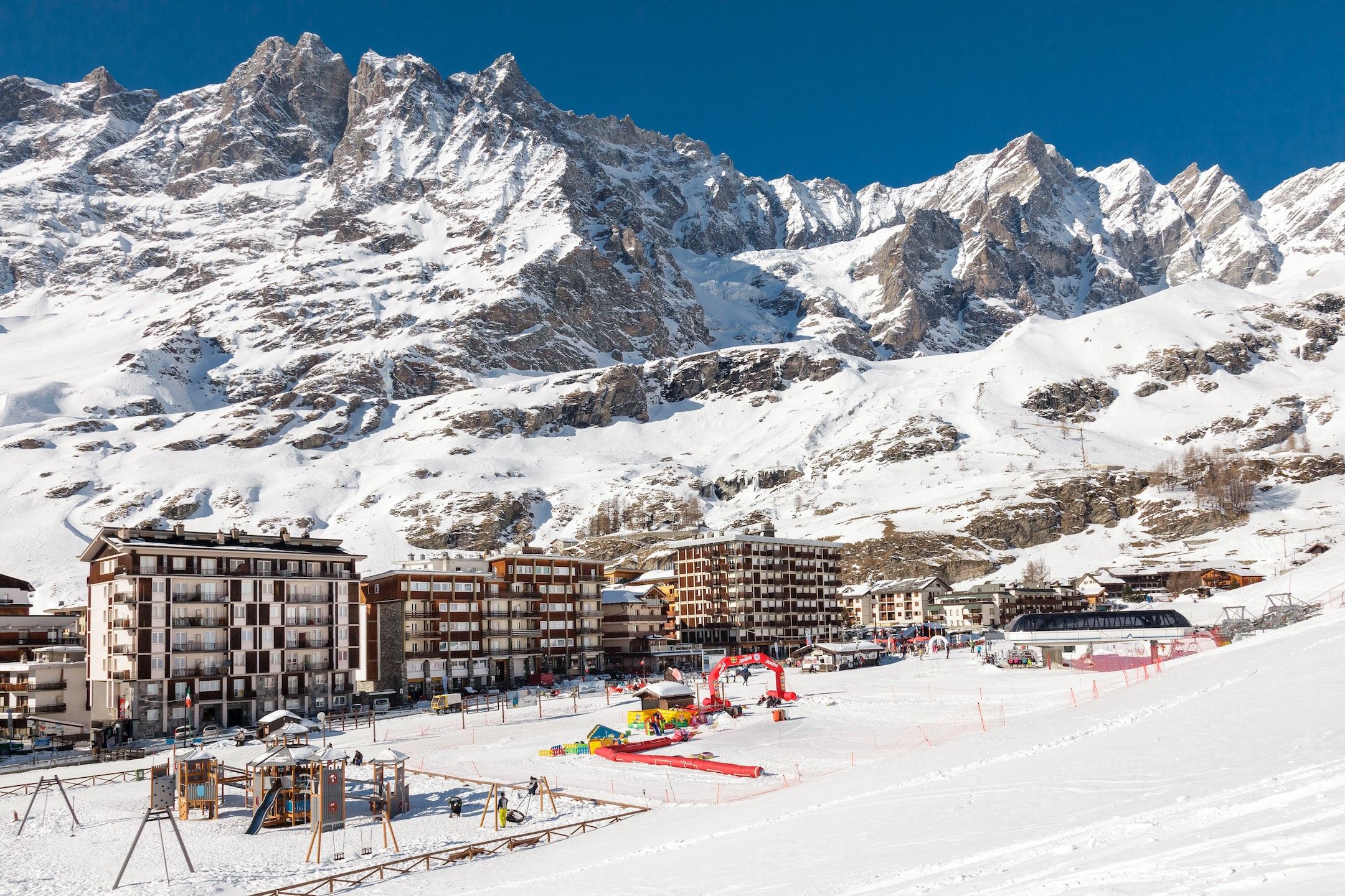 Ein mit Schnee bedeckter Berg mit einem Skigebiet, inklusive Gebäude und Skiliften.