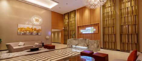A modern lobby with a reception desk, sofas, a coffee table, and a large artwork.