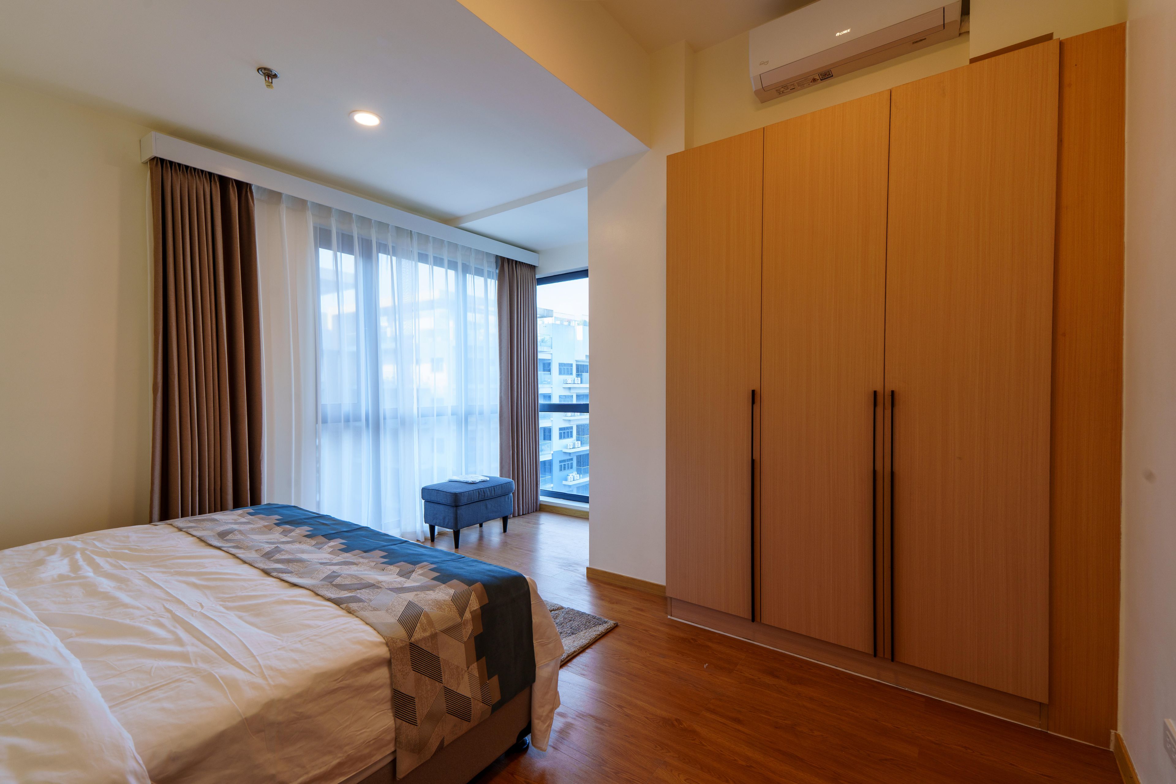 Ein Hotelzimmer mit Bett, großem Kleiderschrank und Blick auf die Stadt.