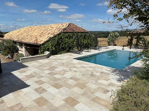 A swimming pool with a tiled deck, a stone building with a tiled roof, and a garden area with benches. - Countryside lodge (Saint-Eutrope-de-Born)