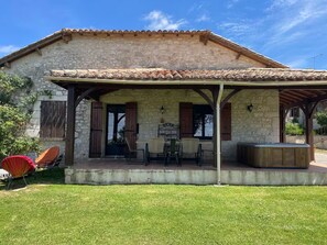 A stone building with a tiled roof, a covered patio with outdoor seating, and a grassy yard. - Countryside lodge (Saint-Eutrope-de-Born)