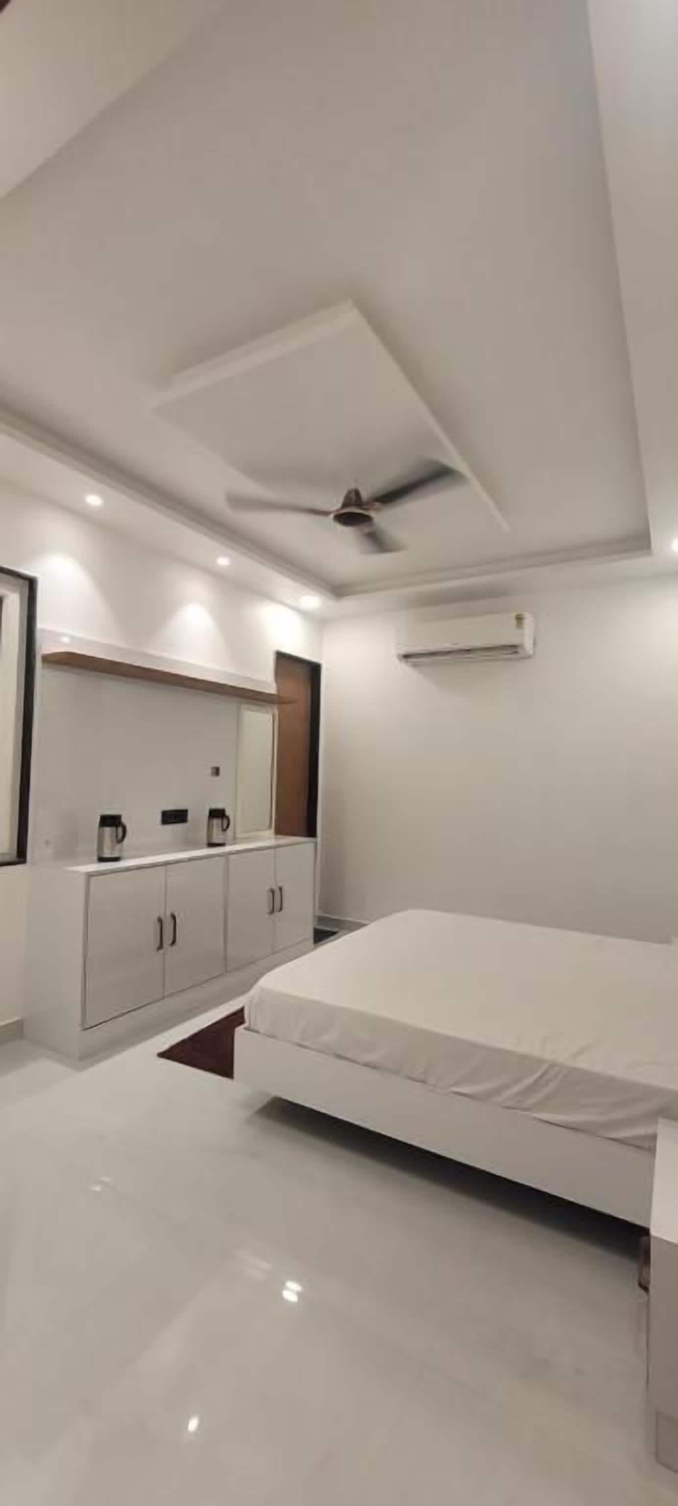 Un dormitorio moderno con cama, armario, ventilador de techo, iluminación empotrada y unidad de aire acondicionado.