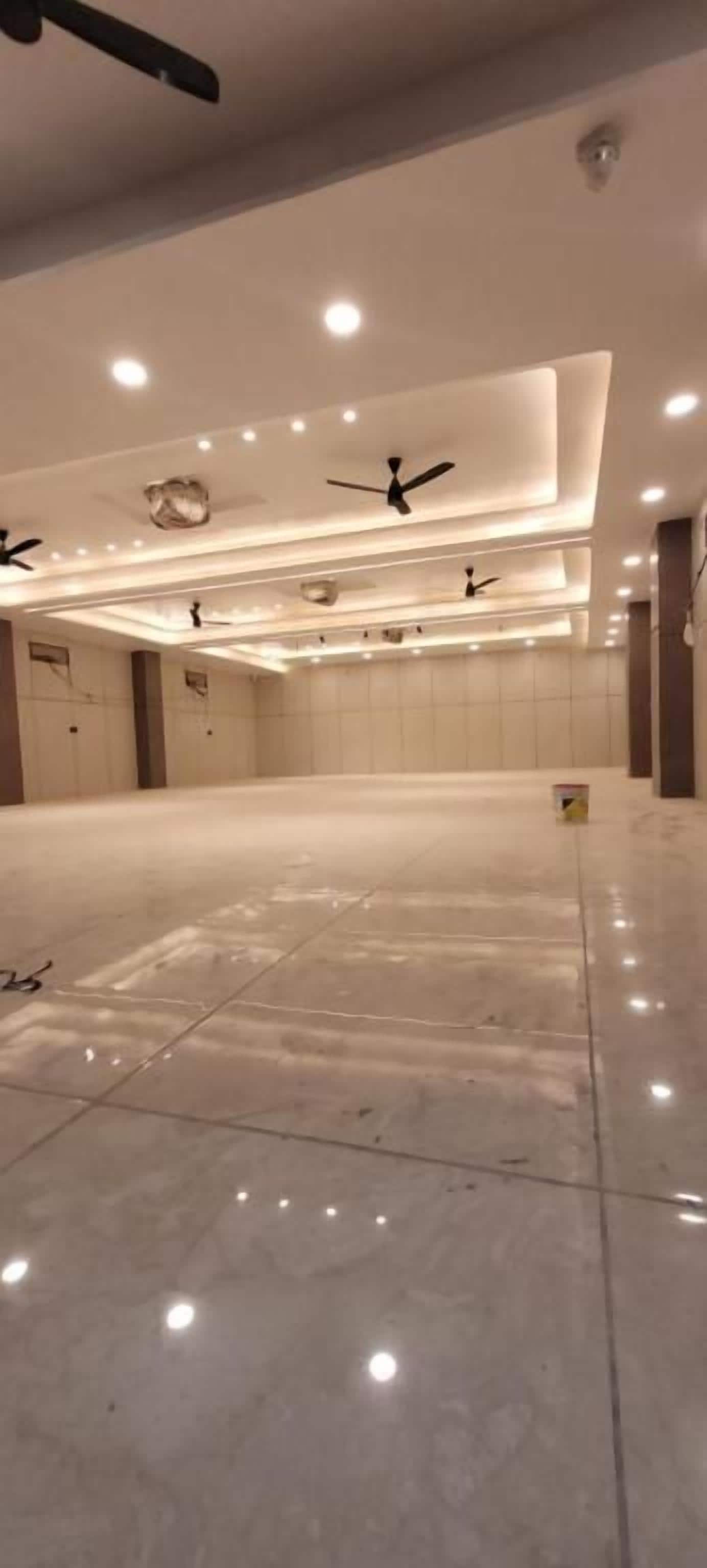 A spacious, well-lit room with a tiled floor, recessed ceiling lights, and ceiling fans.