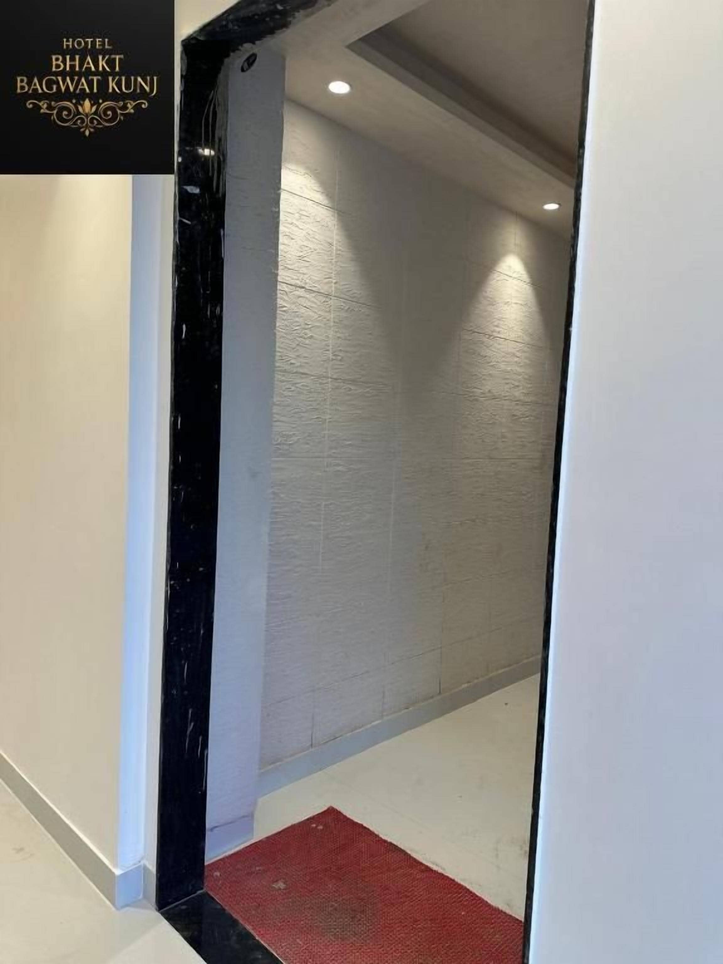 Entrada de hotel con una columna de mármol negro, un felpudo rojo y un cartel con el nombre del hotel.