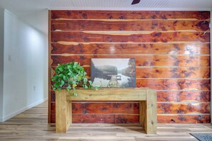 Quarto com painel de parede de madeira e uma mesa de madeira com uma planta e um quadro emoldurado.