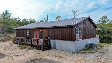 A rustic wooden building with a metal roof, a red door, and a small porch.