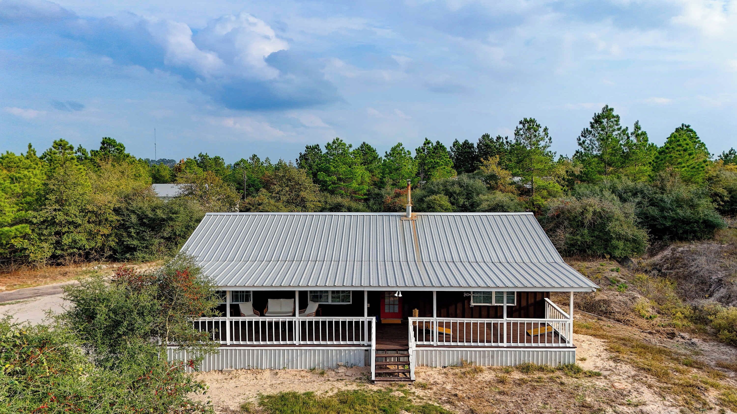 Un bâtiment d’un seul étage, doté d’un toit en métal, entouré d’une forêt dense.