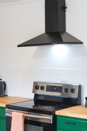 Cozinha com fogão preto, forno de aço inoxidável e exaustor preto.
