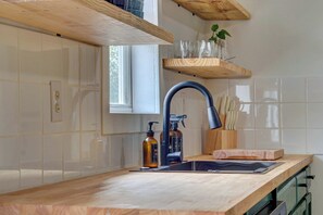 Une cuisine avec un plan de travail en bois, un robinet noir et une fenêtre au-dessus de l’évier.