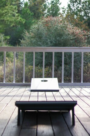 A wooden deck with a white rectangular table and a metal railing. - Bastrop Forest Home | 3BR, Crew & Monthly Stays (Bastrop)