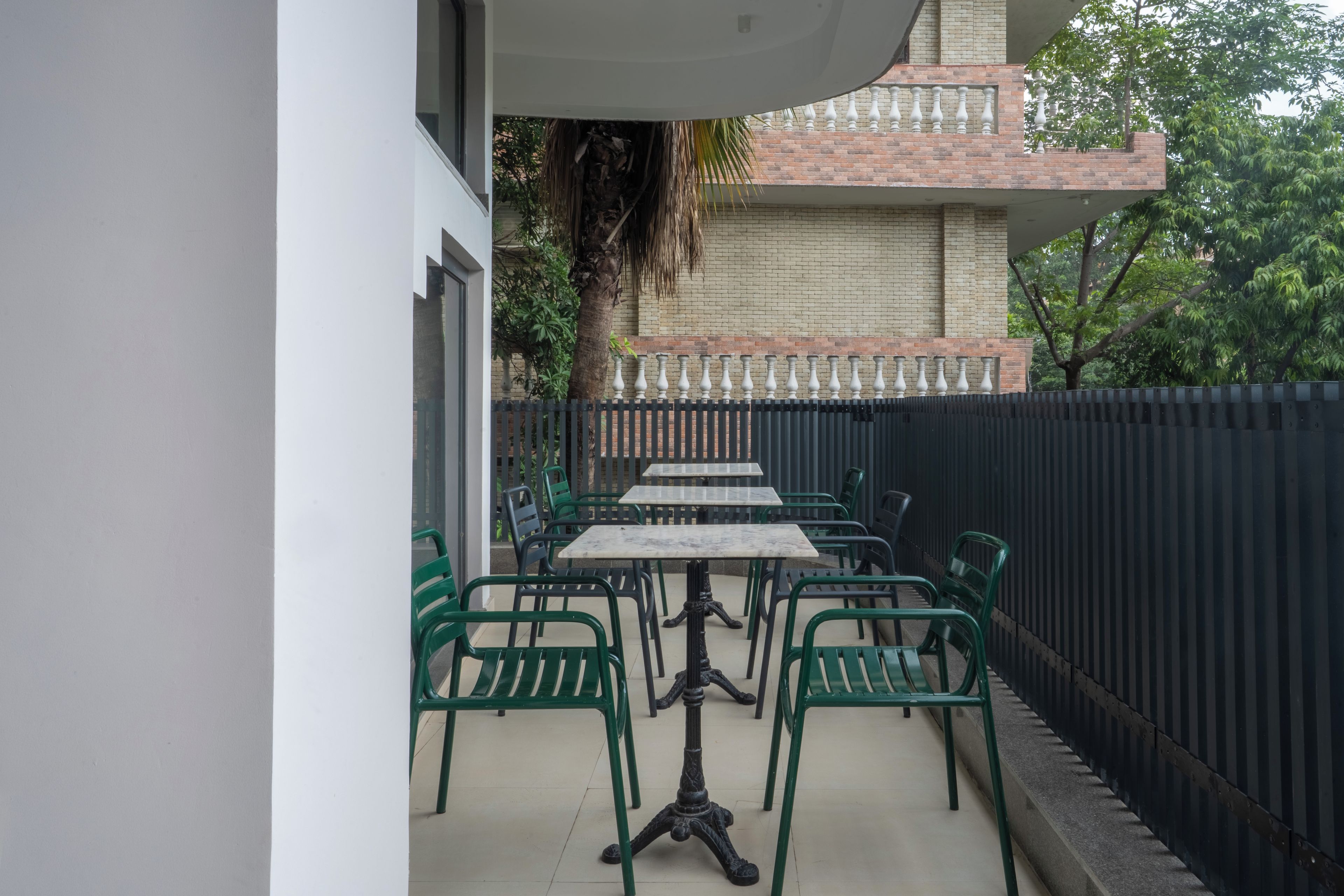 An outdoor patio with a table and chairs, a brick wall, and a metal fence.