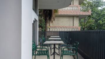 An outdoor patio with a table and chairs, a brick wall, and a metal fence.