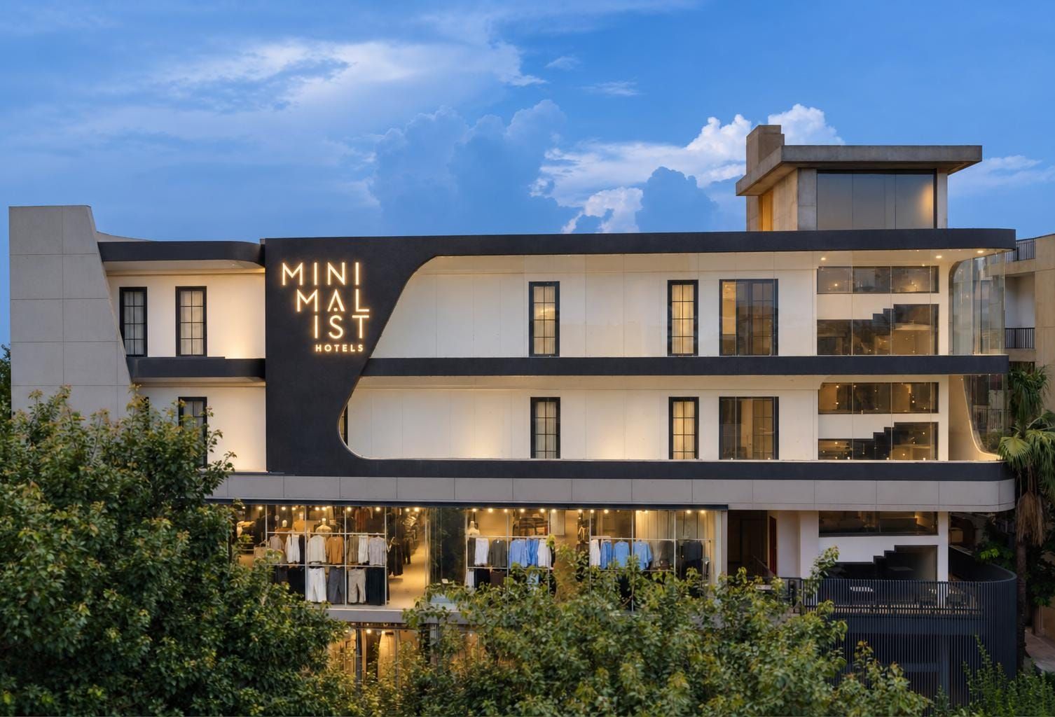 A modern hotel with a prominent sign, multiple floors, and a visible ground-level retail space.