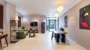 A modern hotel lobby with a sofa, dining table, and artwork on the walls.