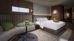 Quarto moderno com cama, área de estar e uma mesinha com um vaso de flores.