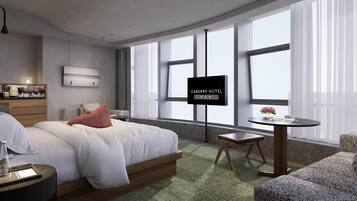 Una habitación de hotel moderna con cama, una mesita, un sofá y una pantalla de televisión mostrando 'CABERRY HOTEL'.