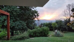 A garden with a wooden pergola, various shrubs, and a view of the sunset over distant mountains. - Villa 'Cubetto' with Wi-Fi and Air Conditioning (Cesena)