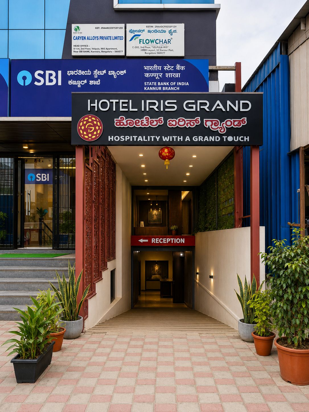 The entrance to Hotel Iris Grand with a reception sign, potted plants, and a staircase leading up to the entrance.