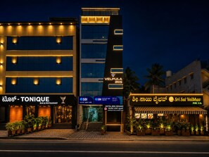 A multi-story building with illuminated signage for VELPULA IRIS and TONIQUE BAR & RESTAURANT. - Hotel Iris Grand (Bengaluru)