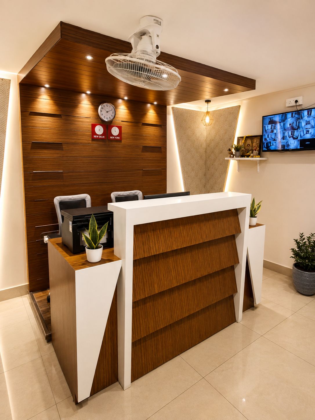 A reception desk with a clock, a television, and a plant.