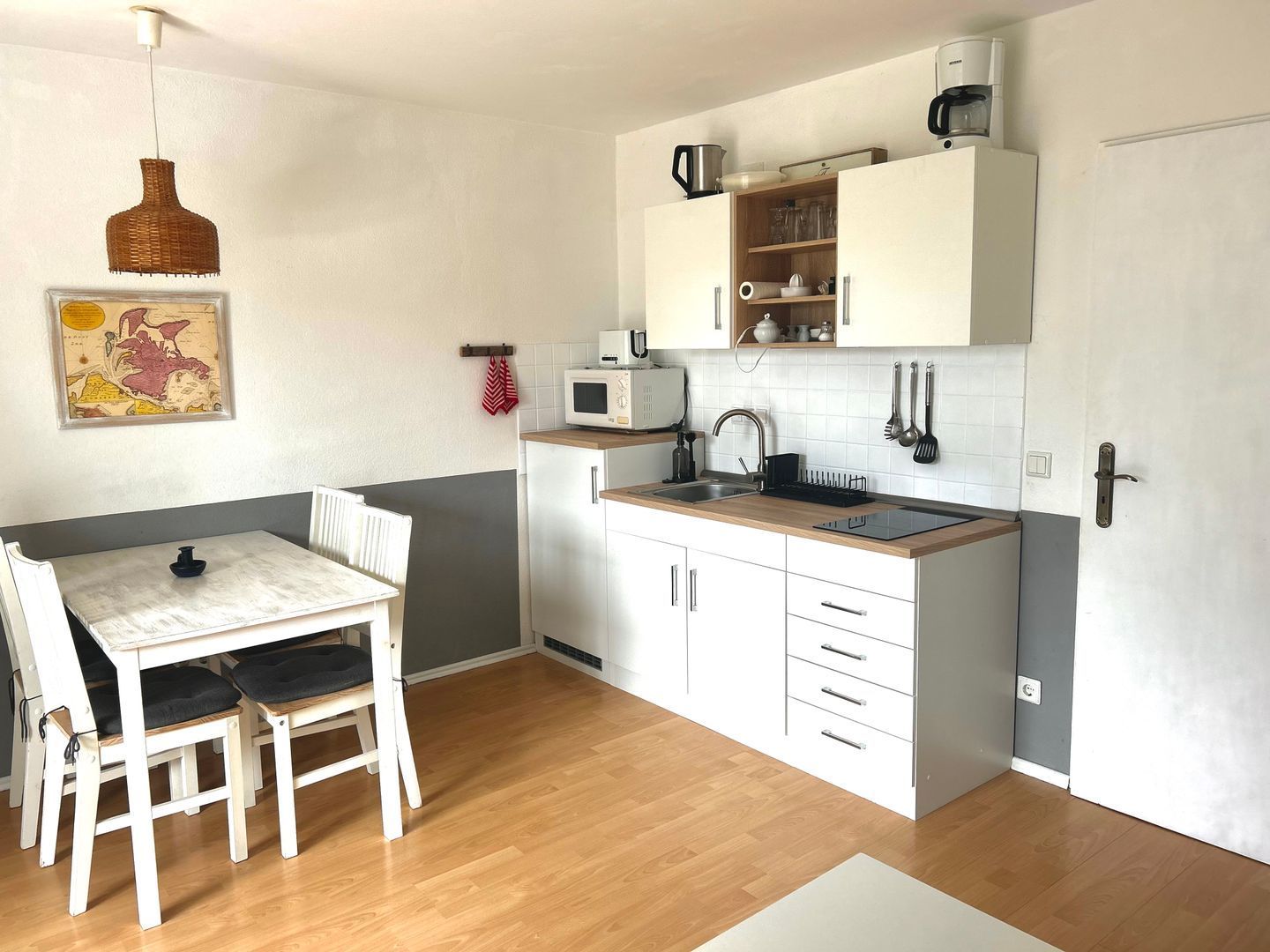 Une cuisine compacte comprenant une table et des chaises, un four à micro-ondes, un évier et des placards.